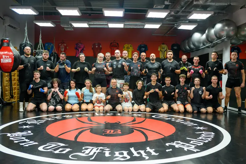 Cała grupa klubowiczów Berserkers Team Rzeszów na macie z logo klubu.